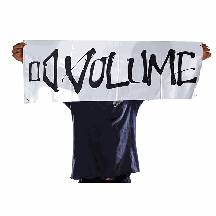 Person holding a white 15x47 inch VOLUME BANNER made of vinyl PVC with black lettering and reinforced hanging holes