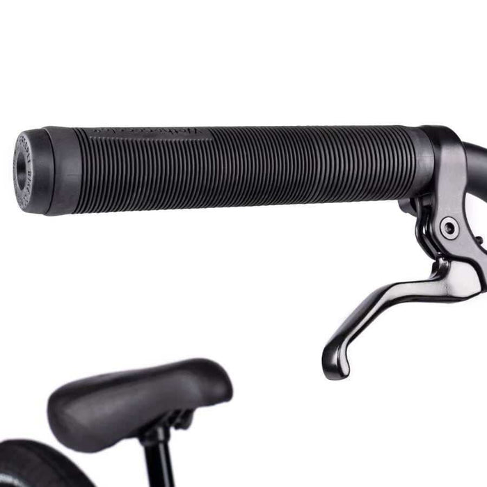 Close-up of black handlebar grip and brake lever on Wethepeople Justice Bike with padded seat in background