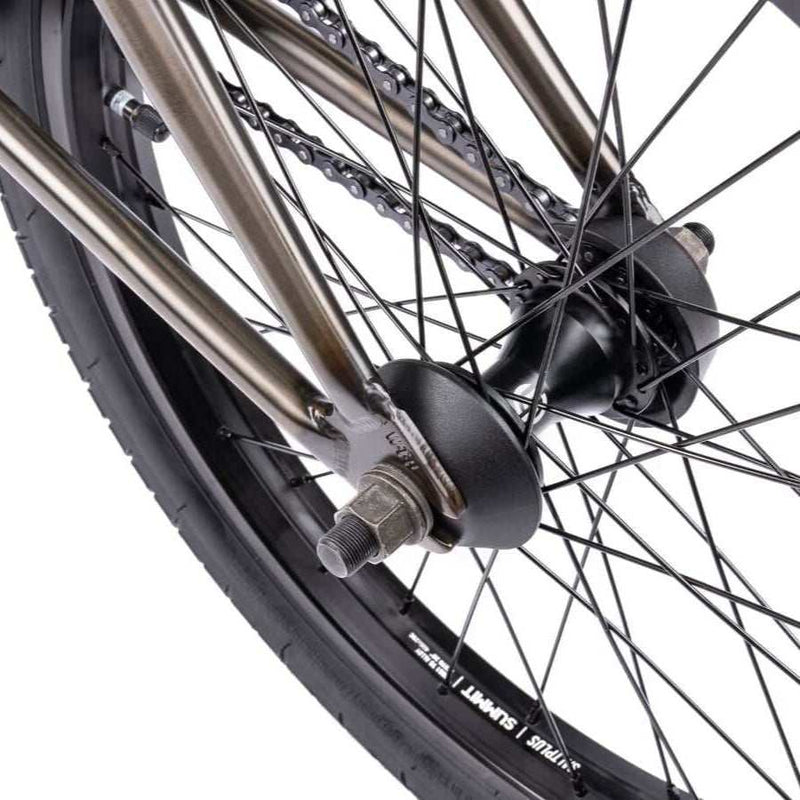 Close-up of the rear wheel and hub of the WETHEPEOPLE JUSTICE BIKE showing the chain, spokes, and part of the frame in metallic color.