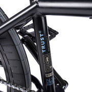 Close-up of WETHEPEOPLE TRUST CS bicycle frame with logo and tire detail.