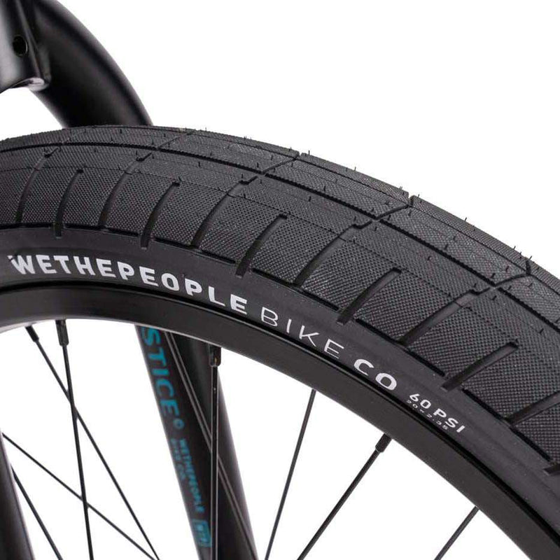Close-up of Wethepeople Justice Bike black tire and wheel with branding on rim and tire tread pattern