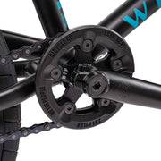 Close-up of Wethepeople Justice Bike black crankset and sprocket with chain and part of the black frame.