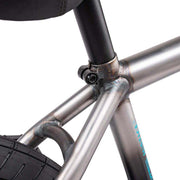 Close-up of the seat tube junction and rear tire of the WETHEPEOPLE JUSTICE BIKE showing metal frame welds and seat post clamp