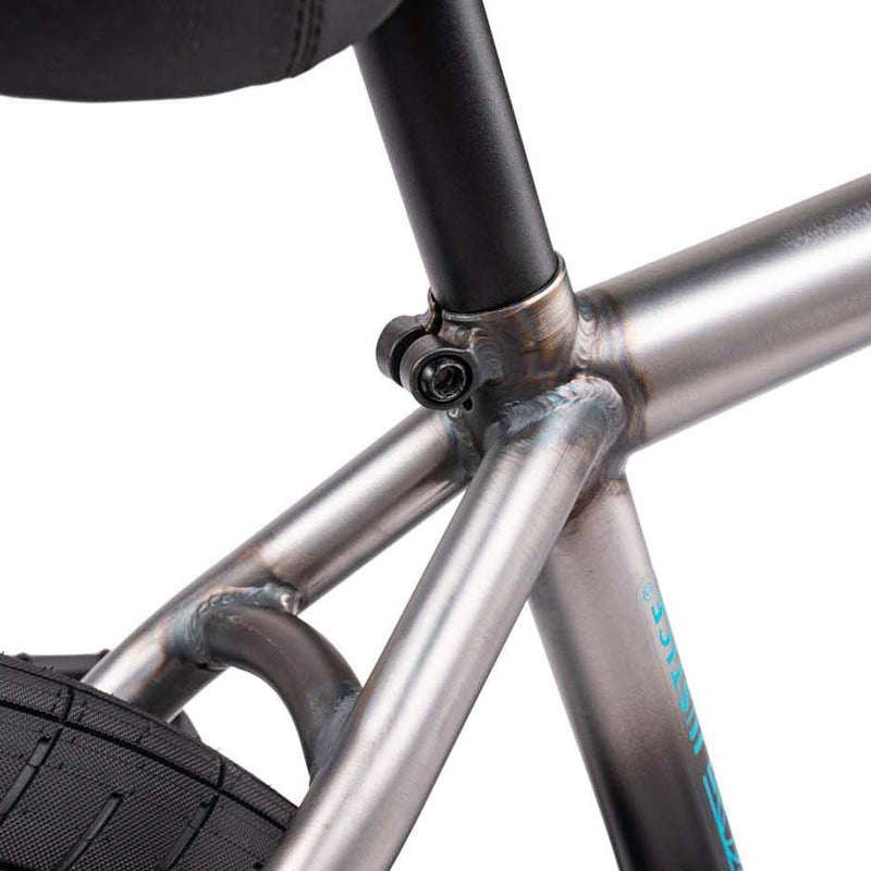 Close-up of the seat tube junction and rear tire of the WETHEPEOPLE JUSTICE BIKE showing metal frame welds and seat post clamp