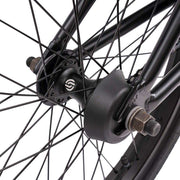 Close-up of Wethepeople Justice Bike rear wheel hub and plastic hub guard with black spokes and axle nuts